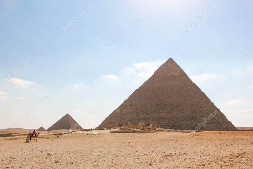View from the desert on a series of pyramids, the three pyramids of the Giza complex with marching riders