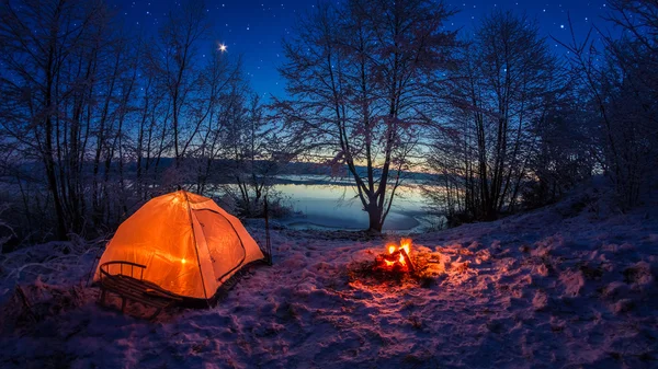 Tenda illuminata nel campo invernale vicino al lago di notte con stelle — Foto Stock
