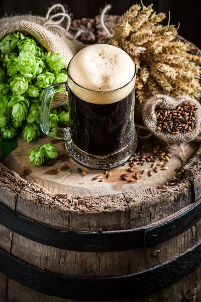 Темне пиво з піною, хмелем і пшеницею — стокове фото