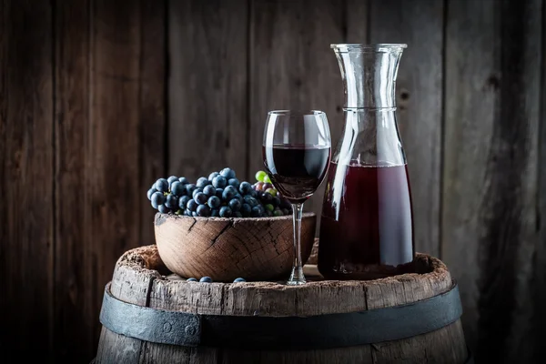 Vinho tinto com uvas frescas em fundo de madeira — Fotografia de Stock