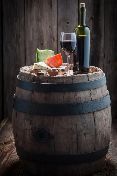 Wine in glass with mix of cheese on old barrel — Stock Photo, Image