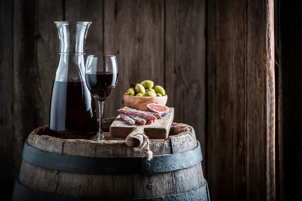 Fresh red wine with cold meats and olives on old barrel — Stock Photo, Image