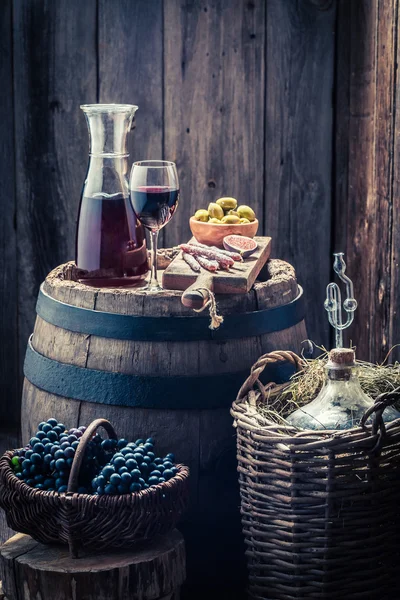 Homemade red wine with olives, cold meats, grapes and demijohn — Stock Photo, Image