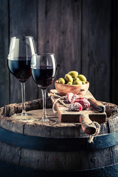 Vinho saboroso em vidro com carnes frias e azeitonas em tábua de madeira — Fotografia de Stock