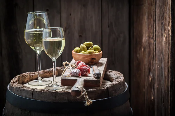 Chardonnay wine with olives and cold cuts on old barrel — Stock Photo, Image