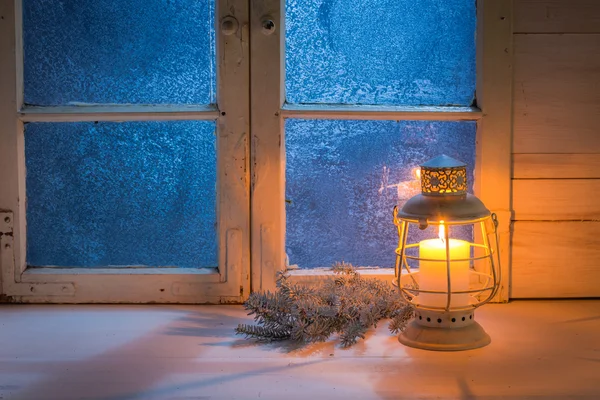 Frosted blue window with burning candle for Christmas at night — Stock fotografie