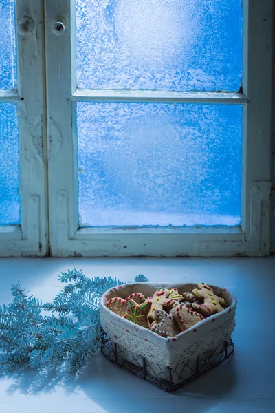 Рождественское печенье на белом столе с замороженным окном — стоковое фото