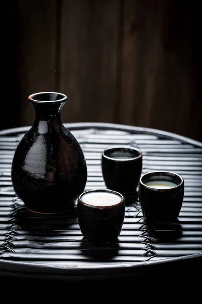 Вкуснейшее саке из черной керамики на черном столе — стоковое фото