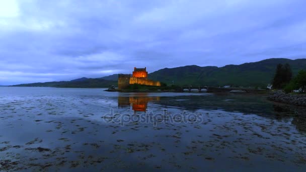 Belysta Eilean Donan Castle över sjön vid solnedgången i Skottland — Stockvideo