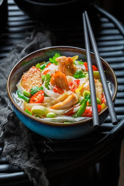 Heerlijke noodle in donkere kom met stokjes — Stockfoto