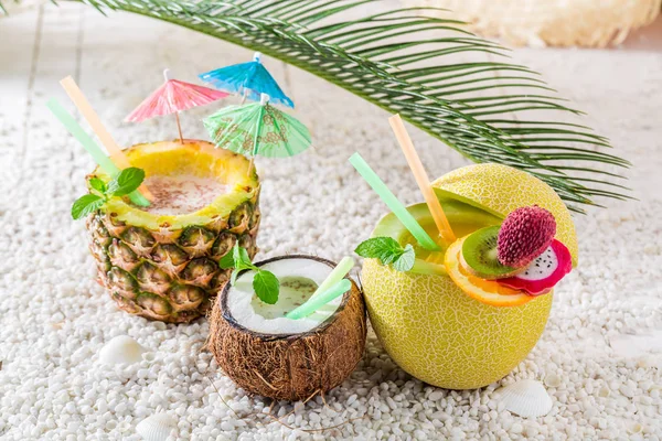 Fräscha drinkar i färsk frukt på sandstrand — Stockfoto