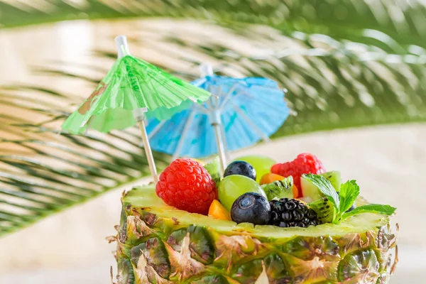 Ensalada de frutas tropicales en piña en la playa de arena —  Fotos de Stock