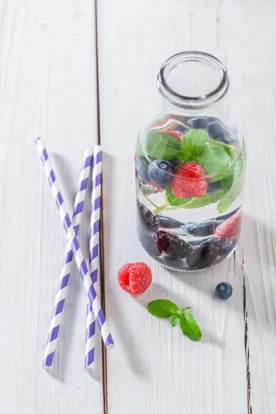Здоровая газировка в бутылке с ягодами и мятными листьями — стоковое фото