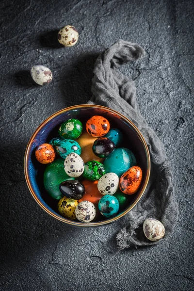 Coloridos huevos de Pascua en tazón azul sobre roca negra —  Fotos de Stock