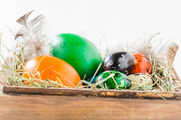 Easter eggs with hay and feathers in wooden box — Stock Photo, Image