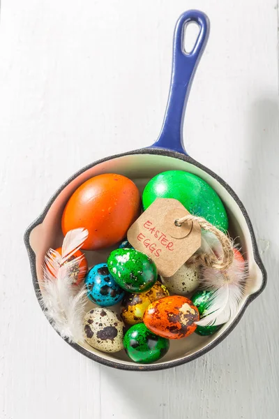 Huevos de Pascua de colores en sartén azul sobre mesa blanca —  Fotos de Stock
