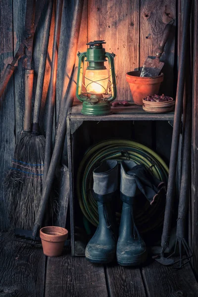 Un antiguo cobertizo rústico con herramientas de jardín y lámpara de aceite — Foto de Stock