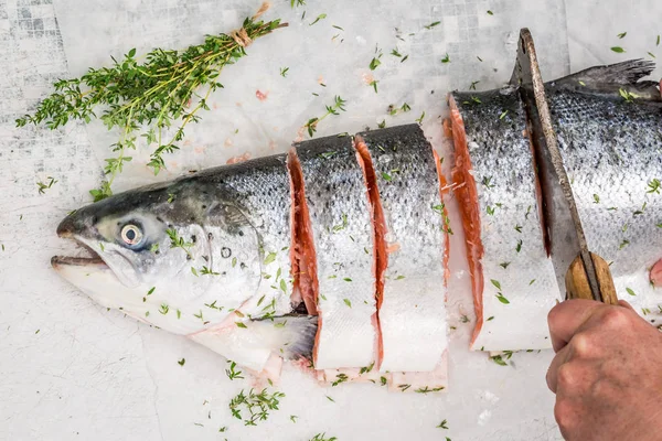 Chopping fresh salmon with lemon and herbs — Stock Photo, Image