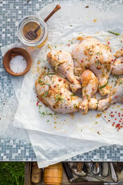 Seasoning chicken legs with honey on an old table