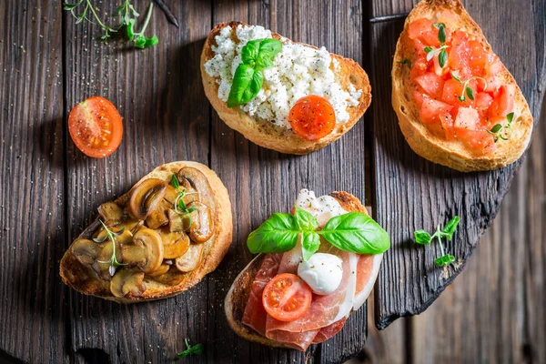 Sabroso distinto bruschetta con los ingredientes frescos para la colación — Foto de Stock