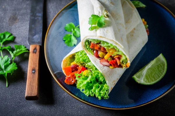 Primo piano di burrito con verdure, salsa piccante e lime — Foto Stock