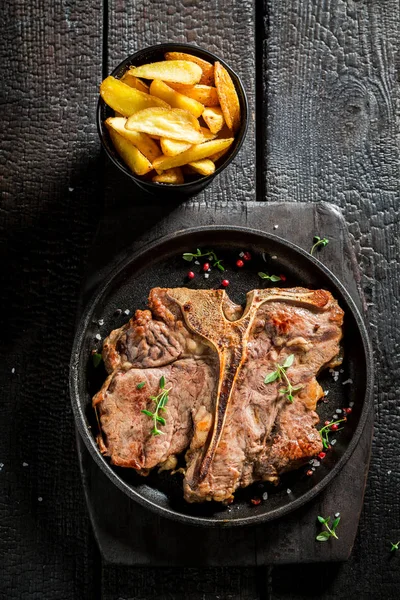 Tasty chips and tbone steak on the burnt table — Stock Photo, Image
