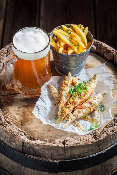 Smelt fish with cold beer and chips on old barrel — Stock Photo, Image
