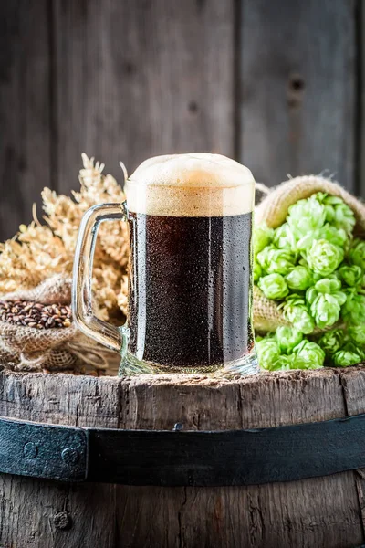 Pint of dark beer on old oak barrel — Stock Photo, Image