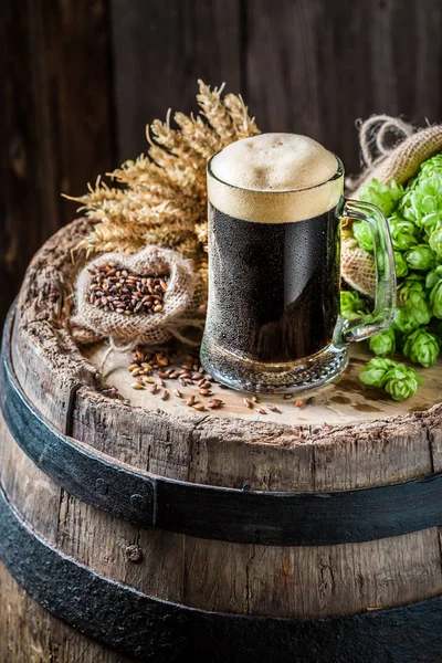 Cold dark beer on oak barrel with hops and wheat — Stock Photo, Image