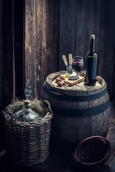 Red wine with cheese and demijohn in basement — Stock Photo, Image
