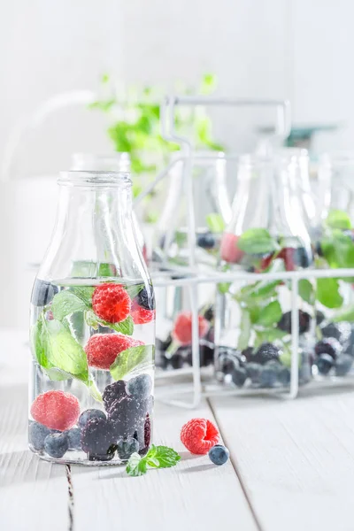 Soda frizzante in bottiglia con bacche su tavolo bianco — Foto Stock
