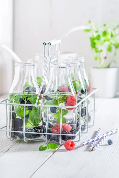 Fresh water in bottle with berries on white table — Stock Photo, Image