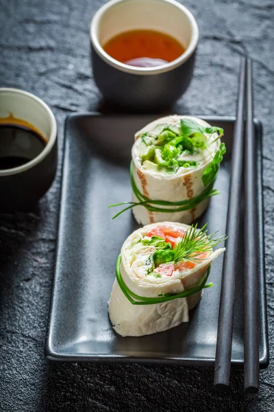 Delicious rolls with salmon, cheese and vegetables on dark rock — Stock Photo, Image