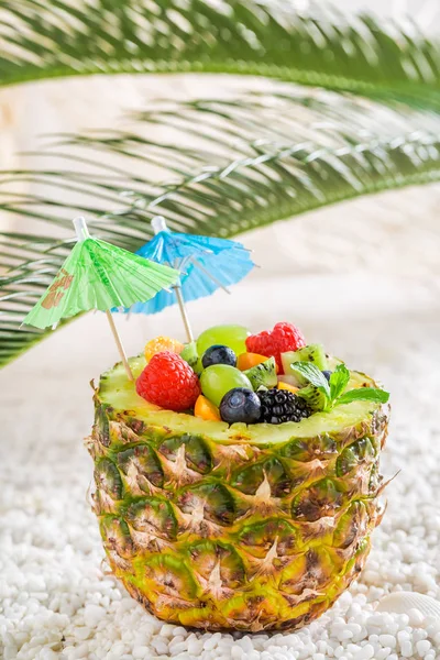 Närbild av tropiska fruktsallad i ananas med cocktail paraplyer — Stockfoto