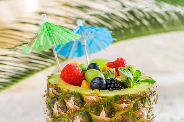 Närbild av fruktsallad i ananas med cocktail paraplyer — Stockfoto