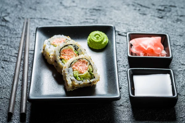 Lekkere sushi gemaakt van zalm en avocado op zwarte rots — Stockfoto