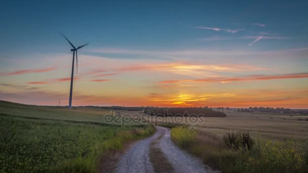 Pôr do sol bonito sobre um campo com um moinho de vento e estrada rural, timelapse, 4K — Vídeo de Stock