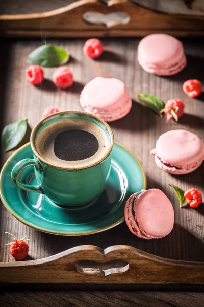 Smakelijke roze bitterkoekjes geserveerd met warme koffie — Stockfoto