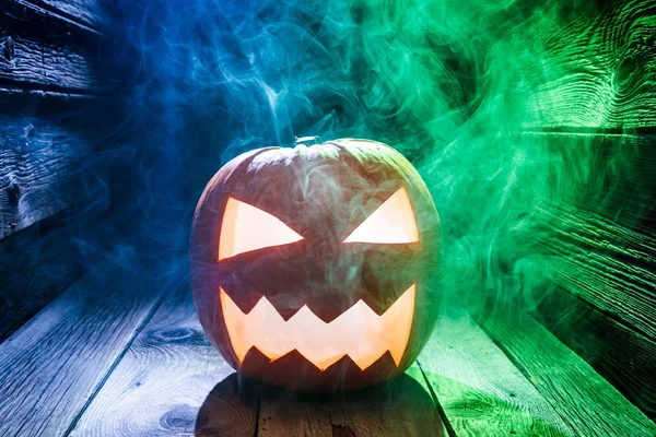 Zářící dýně na Halloween s kouře na dřevěné desce — Stock fotografie