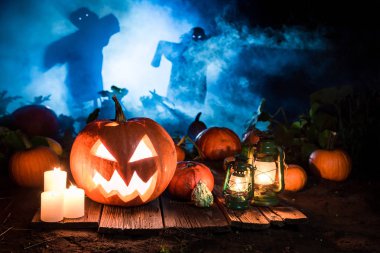 Orange pumpkin on dark field with scarecrows for Halloween clipart