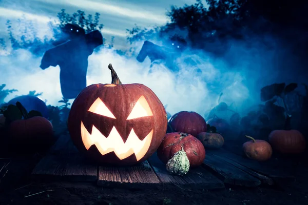 Glödande Halloween pumpa på mörka fält med fågelskrämmor — Stockfoto