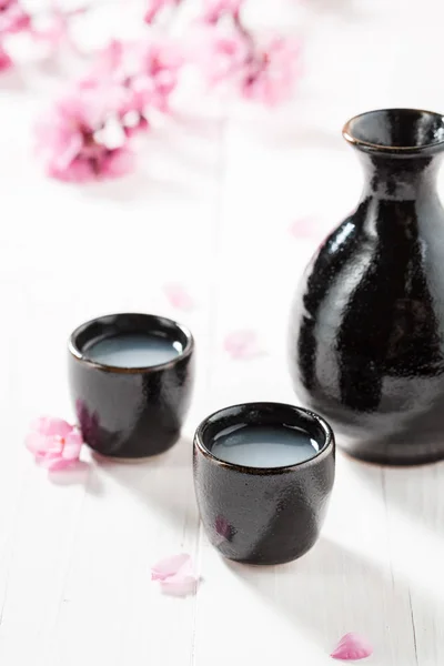 Ongefilterde witte sake sake met bloemen van bloeiende kers — Stockfoto