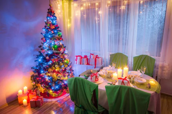 Weihnachtstisch gedeckt mit Weihnachtsbaum und Geschenken am Abend — Stockfoto