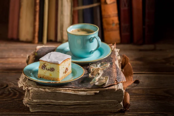 Rustieke cheesecake en koffie op boek in bibliotheek — Stockfoto