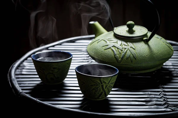 Closeup of herbal tea with teapot on black bamboo table — Stock Photo, Image