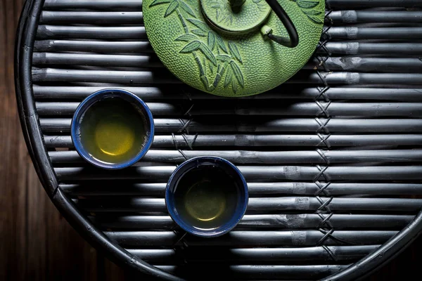 Closeup de chá verde com bule na mesa de bambu preto — Fotografia de Stock