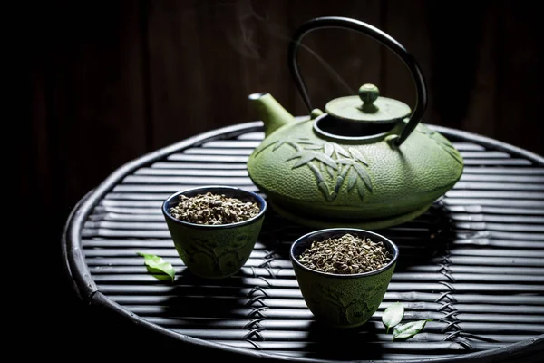 Fresh tea with teapot on black bamboo table — Stock Photo, Image