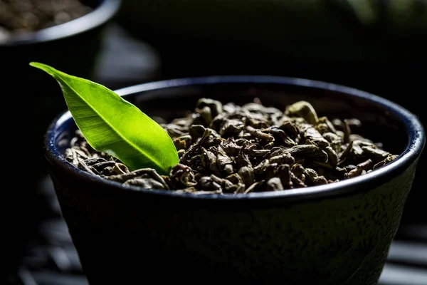 Closeup de grãos de chá verde em xícara de chá preta — Fotografia de Stock