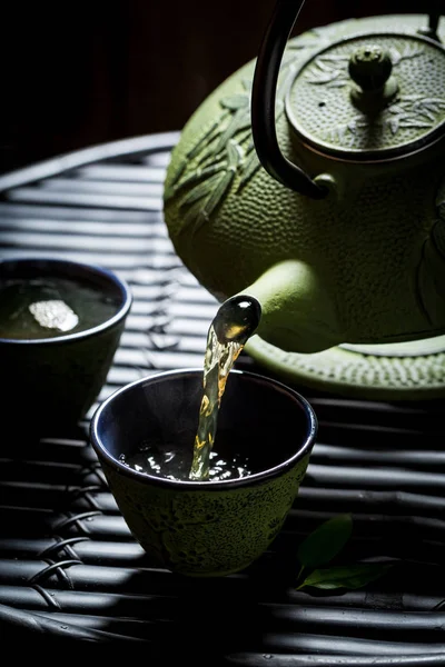 Pouring green tea into tea cup from with teapot — Stock Photo, Image