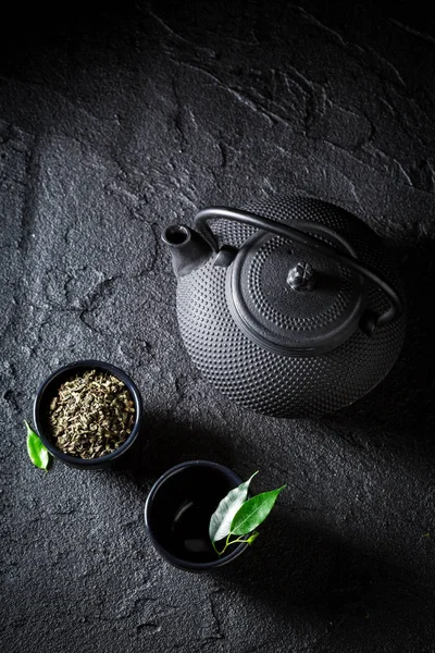 Grains of green tea in teacup on black rock — Stock Photo, Image